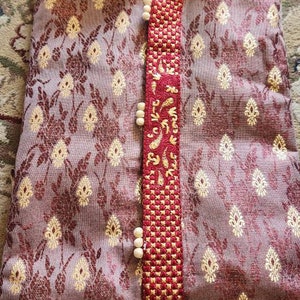 Op de afbeelding: Een maron kurta met een gouden en rood geborduurd ontwerp. De kurta heeft een knoopsluiting en een kraag.