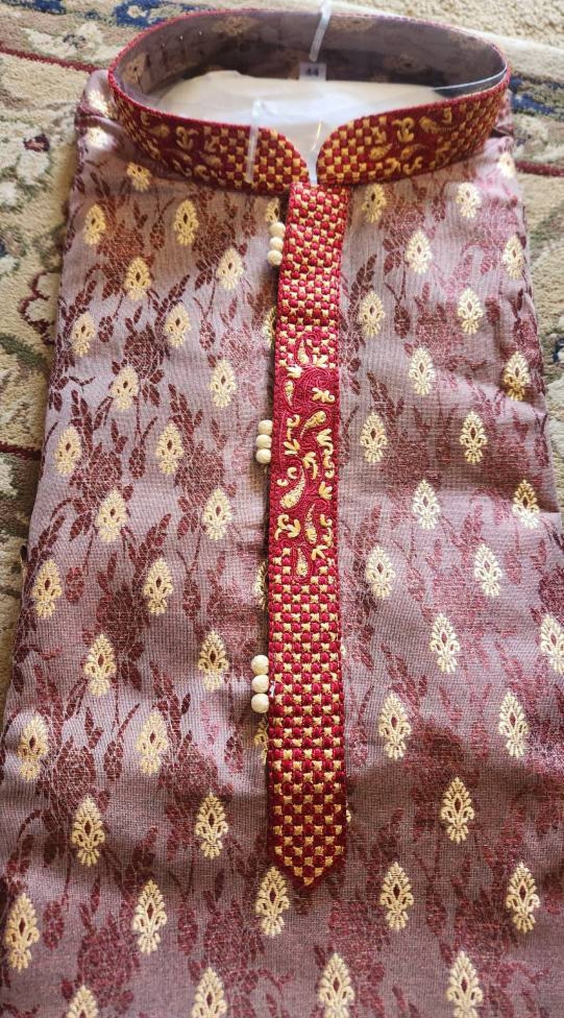 Op de afbeelding: Een maron kurta met een gouden en rood geborduurd ontwerp. De kurta heeft een knoopsluiting en een kraag.