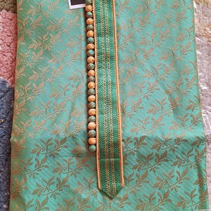 May include: A mint green kurta pajama set with a gold floral pattern. The kurta features a mandarin collar and a decorative strip with wooden beads. The label reads "I.ELEGANT".