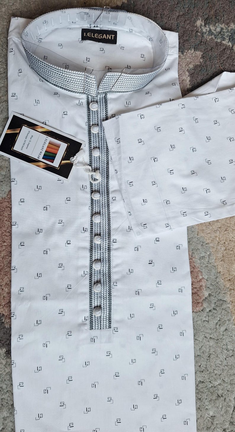 May include: White kurta with a geometric pattern and a mandarin collar. The kurta features a button-down front with decorative trim and a tag that reads "I.ELEGANT WEAR".