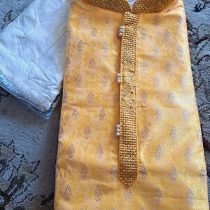 Op de afbeelding: Een gele kurta met een bloemenpatroon en een kralenbies. De kurta heeft een mandarijnkraag en een knoopsluiting. Het maatlabel geeft "42" aan.
