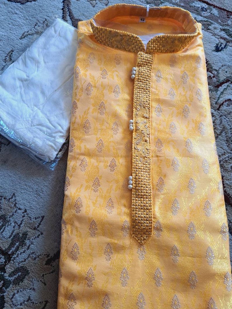 Op de afbeelding: Een gele kurta met een bloemenpatroon en een kralenbies. De kurta heeft een mandarijnkraag en een knoopsluiting. Het maatlabel geeft "42" aan.