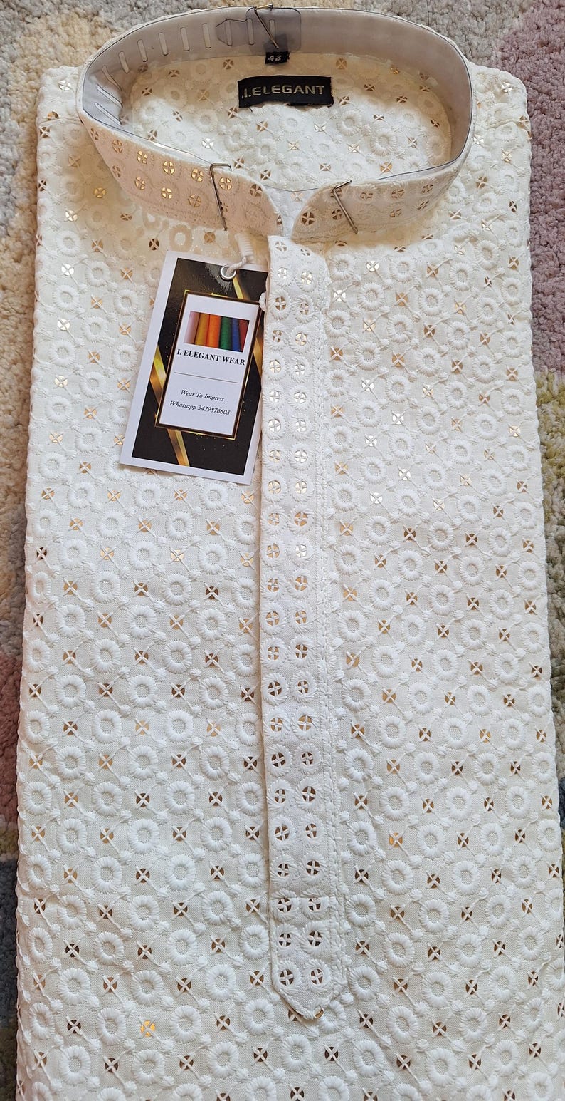 Puede incluir: Una kurta de algod&oacute;n blanco con bordados dorados. La kurta tiene un cuello mandar&iacute;n y un cierre de bot&oacute;n. La tela es ligera y transpirable, lo que la hace perfecta para el clima c&aacute;lido. La kurta es una prenda tradicional india que a menudo se usa para ocasiones especiales.