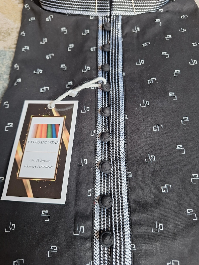 May include: Black button-down shirt with a white and black striped accent on the placket and collar. The shirt has a repeating white geometric pattern. A tag with the text "L. ELEGANT WEAR" is attached.