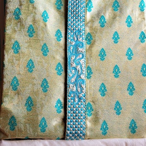 Op de afbeelding: Een lichtgroene kurta met een blauwe en witte geborduurde rand. De kurta heeft een traditioneel Indiaas ontwerp en is gemaakt van een zijdeachtige stof.