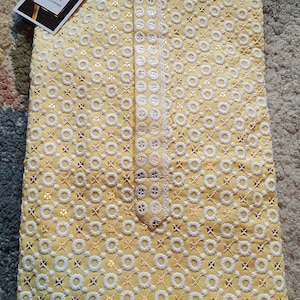 May include: A yellow kurta with white embroidery and sequins. The kurta has a mandarin collar and a button closure. The fabric is lightweight and breathable, making it perfect for warm weather.