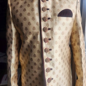 May include: A gold and burgundy patterned long-sleeved jacket with a high collar and a row of decorative buttons down the front.