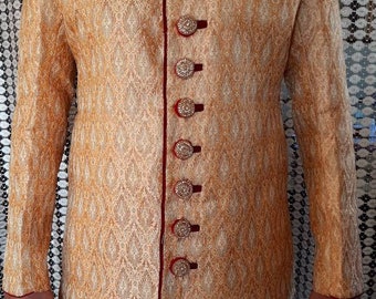 May include: A long, gold-colored jacket with a red trim and decorative buttons. The jacket has a traditional Indian design.