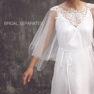 Può includere: Abito da sposa bianco con un rivestimento trasparente e dettagli in pizzo floreale intorno allo scollo. L'abito ha uno scollo a V e una vita con fiocco. Le parole "BRIDAL SEPARATES" sono stampate in alto a sinistra nell'immagine.
