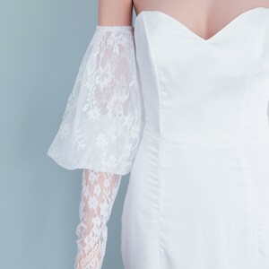 May include: White off-the-shoulder bridal separates with a lace overlay. The lace sleeves are long and have a puffed, bell-shaped design. The text "BRIDAL SEPARATES" is visible at the top of the image.