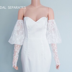 May include: White off-the-shoulder bridal dress with lace sleeves. The dress has a sweetheart neckline and a fitted silhouette. "BRIDAL SEPARATES" is written in the top left corner of the image.