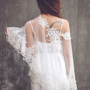 May include: A white lace overlay with a delicate floral pattern. The overlay is sheer and has a flowing, romantic style.