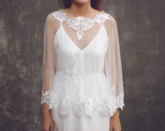 May include: A white lace overlay with a delicate floral design. The overlay is sheer and has a flowing silhouette. It is perfect for adding a touch of elegance to any outfit.