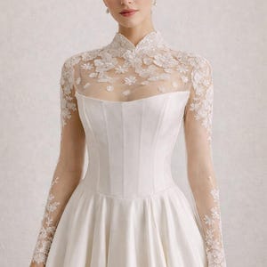 May include: A white bridal gown with a high, lace-detailed neckline and long, sheer sleeves. The bodice is fitted, and the skirt flares out. The text "BRIDAL SEPARATES" is at the bottom.