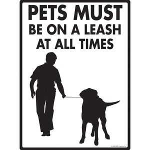 May include: Black and white sign with the text "Pets Must Be On A Leash At All Times". A silhouette of a person walking a dog on a leash is shown.