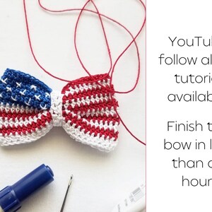 May include: A crocheted bow tie in red, white, and blue, resembling the American flag. The bow tie is tied with red yarn. The text "YouTube follow along tutorial available! Finish the bow in less than an hour!" is visible in the image.