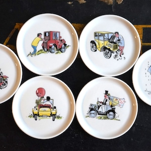 Peut inclure: Six sous-verres en céramique blanche avec des illustrations colorées de voitures anciennes et de personnes. Chaque sous-verre présente une scène différente avec une voiture, un conducteur et un passager.