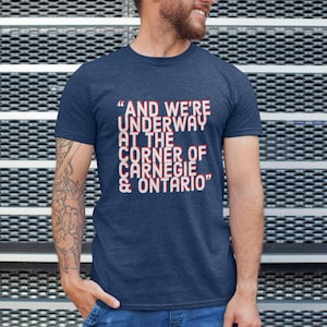 May include: A navy blue t-shirt with a white graphic print that reads "AND WE'RE UNDERWAY AT THE CORNER OF CARNEGIE & ONTARIO"