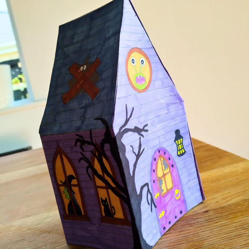 Completed printable 3D haunted house showcasing how the rear looks upclose . The model is vividly colored and features detailed Halloween elements including a alien, lanthern and a large door.