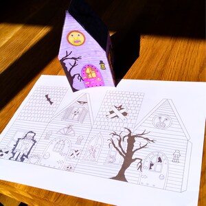 Printable layout displaying all sides of the 3D haunted house in 2D form. Features Halloween figures including a zombie, pumpkin, ghost, alien, and a large black tree.