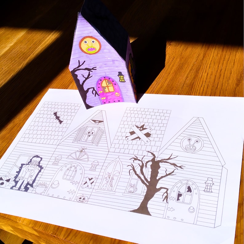 Printable layout displaying all sides of the 3D haunted house in 2D form. Features Halloween figures including a zombie, pumpkin, ghost, alien, and a large black tree.