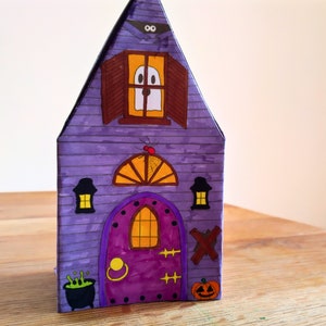 Completed printable 3D haunted house showcasing how the front looks upclose . The model is vividly colored and features detailed Halloween elements including a pumpkin, ghost, spider, and a large front door.