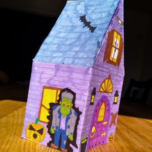 Completed printable 3D haunted house showcasing how the left side looks upclose . The model is vividly colored and features detailed Halloween elements including a zombie, black bat and a pumpkin.
