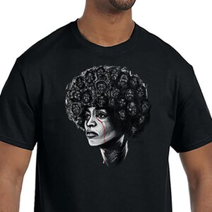 May include: A black t-shirt with a graphic of a woman with an afro hairstyle. The woman's face is drawn in black and white, with a single red tear running down her cheek. The afro is made up of many smaller faces, all drawn in black and white.