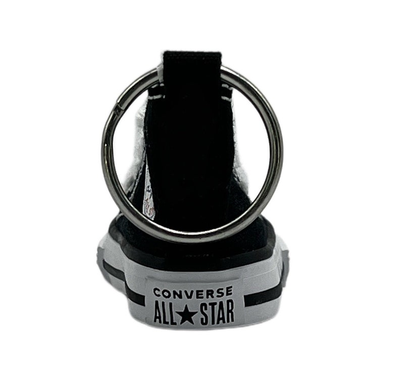 May include: Black Converse All Star shoe keychain with a silver key ring. The shoe has white accents and the text "Converse All Star" on the side.