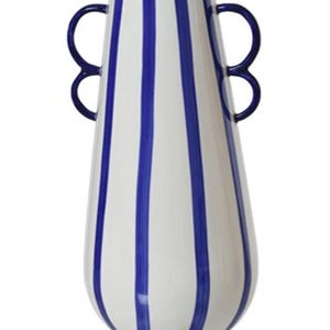 May include: A tall, tapered ceramic vase featuring a white base with vertical royal blue stripes. The vessel has a narrow neck and two symmetrical, rounded blue handles attached to the upper sides, creating a balanced and functional silhouette.