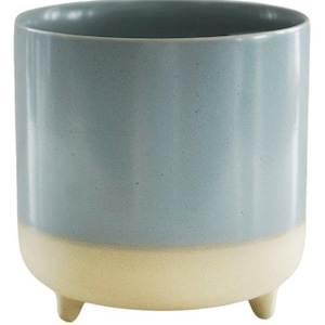 May include: A two-tone ceramic planter. The upper section is light blue, the base cream-coloured. The cylindrical planter rests on three small, rounded feet. The interior is a darker shade of blue.