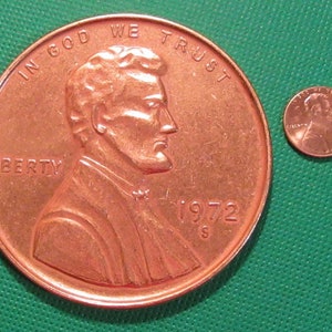 May include: A large copper penny with the image of Abraham Lincoln on the front. The coin says "In God We Trust" and "Liberty" on the front and "1972 S" on the back. A smaller copper penny is shown next to the larger penny.