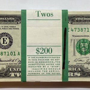 May include: A stack of two dollar bills with a green band around them. The band says "Twos" and "$200". The text on the band also says "If the numbers on notes in this package do not run in sequence, the substituted notes are indicated by a "star". Inquiries should include the serial numbers of the notes."