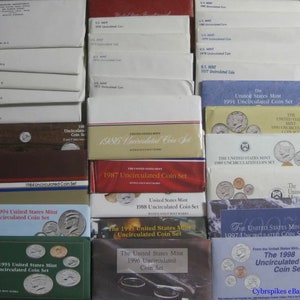 May include: A collection of United States Mint Uncirculated Coin Sets from 1984 to 1998. The sets are displayed in their original packaging, which features a variety of colors and designs. The sets are arranged in chronological order, with the oldest set on the left and the newest set on the right.