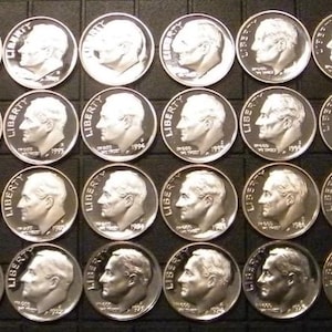 May include: A collection of silver dimes arranged in rows. Each coin features a profile of a man and the word "Liberty". The coins are displayed on a dark, textured surface.