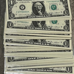 May include: A stack of twenty US one dollar bills, each featuring a portrait of George Washington and the text "THE UNITED STATES OF AMERICA" and "ONE DOLLAR".