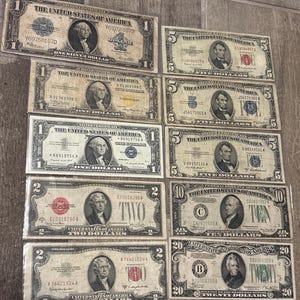 May include: A collection of ten vintage United States banknotes arranged in two columns, featuring various denominations including one-dollar silver certificates, two-dollar bills with red seals, five-dollar notes, a ten-dollar bill, and a twenty-dollar bill.
