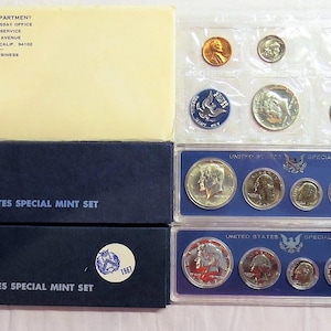 May include: Two blue boxes with the text "United States Special Mint Set" and the years 1965 and 1967. The boxes contain sets of silver coins in plastic cases. The coins are from the United States Mint.