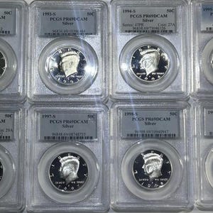 May include: A collection of ten silver US half-dollar coins in protective plastic cases. The coins are dated from 1992 to 1999 and graded by PCGS as PR69DCAM. Each case has a label with the year, coin grade, and serial number.
