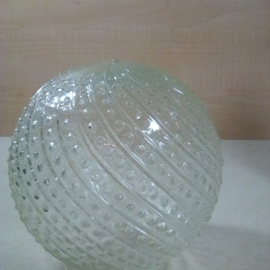 May include: A clear glass globe light fixture with a textured, swirling pattern of raised dots.