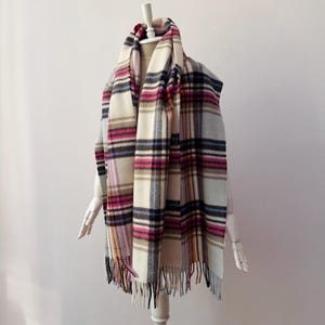 May include: A white, blue, pink, and brown plaid scarf with fringe on the ends.