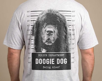 Puede incluir: Una camiseta gris claro de manga corta con un gráfico en blanco y negro de un perro en la espalda. El gráfico incluye una escala de altura tipo ficha policial y el texto "POLICE DEPARTMENT", "DOOGIE DOG" y "Being Aloof" en negro.