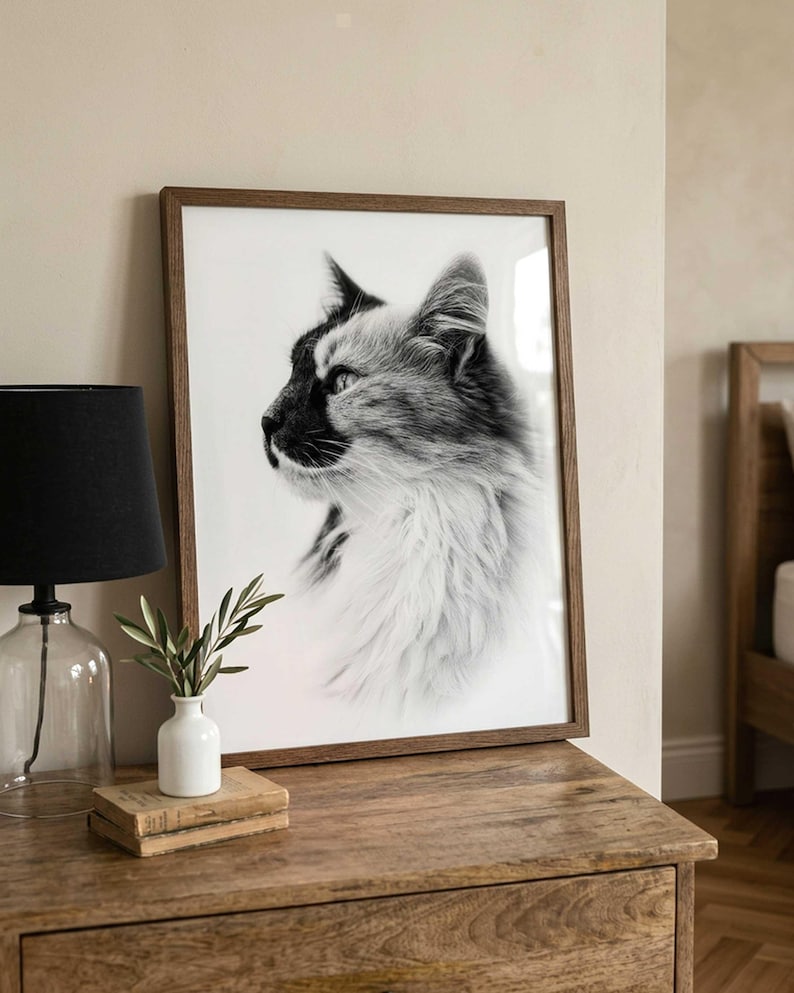 May include: A rectangular wall art print featuring a black and white profile portrait of a long-haired cat. The print is encased in a thin, medium-toned wooden frame, showcasing the cat's detailed fur texture and focused gaze in high contrast.