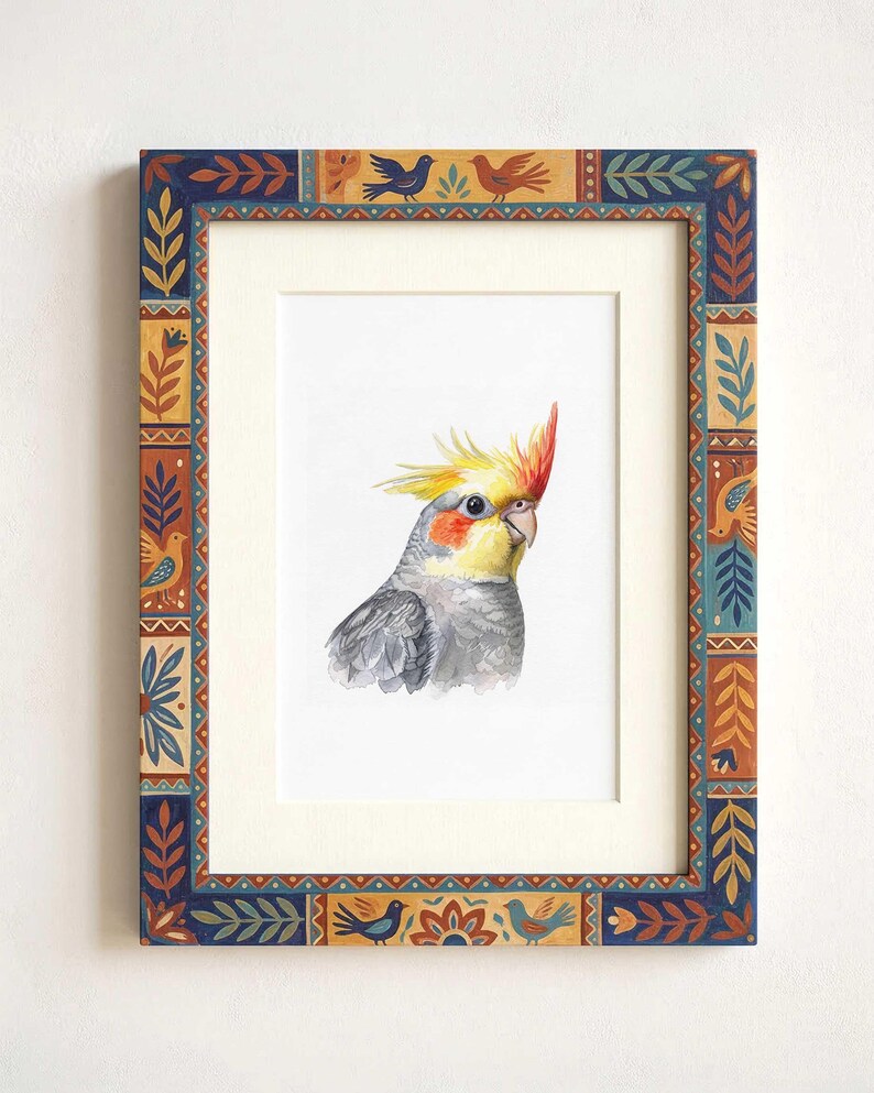 May include: A framed watercolor painting of a cockatiel with a yellow crest, orange cheek patches, and gray feathers. The frame features a decorative border with repeating patterns of blue, orange, and yellow birds, leaves, and geometric shapes.