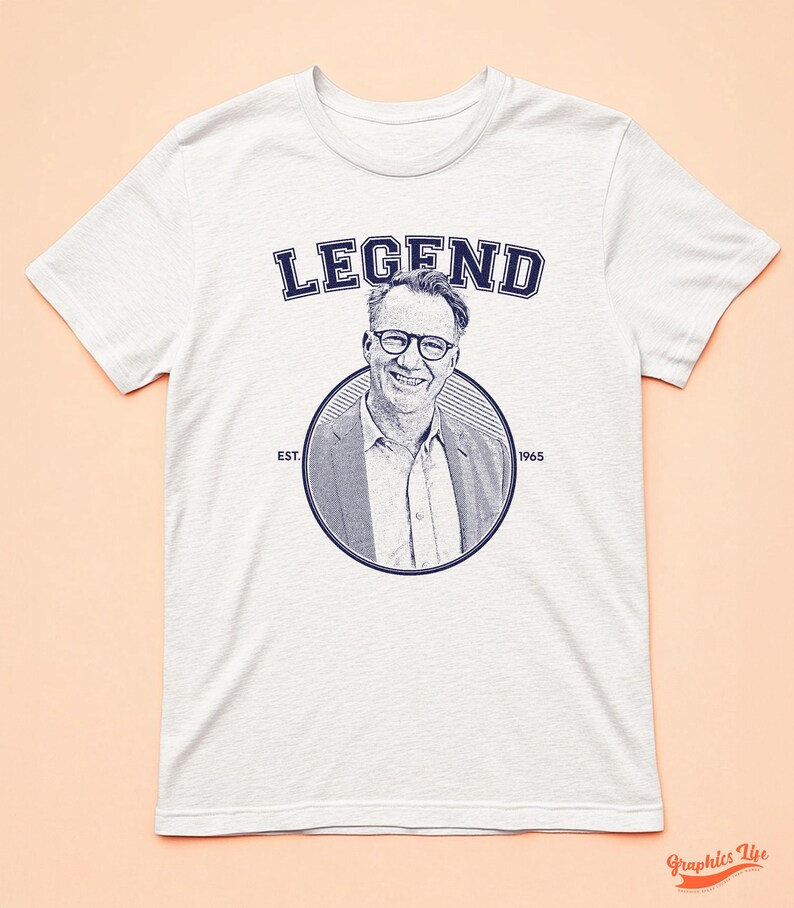 May include: White t-shirt with a blue graphic of a man wearing glasses and the text "LEGEND EST. 1965".