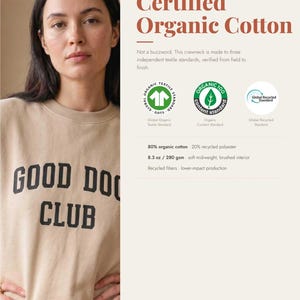 May include: A beige crewneck sweatshirt featuring the black text GOOD DOG CLUB on the front. The garment is composed of 80% organic cotton and 20% recycled polyester, weighing 8.3 oz, with a soft brushed interior and certified textile standards.