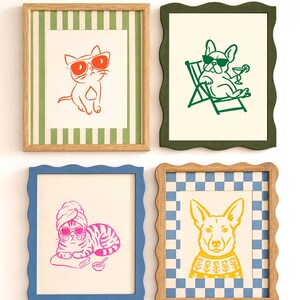 Op de afbeelding: Vier ingelijste wandkunstwerken met dierillustraties. Linksboven: oranje kat met zonnebril in een groen gestreepte lijst. Rechtsboven: groene hond in een ligstoel in een golvende donkergroene lijst. Linksonder: roze kat met handdoek in een golvende blauwe lijst. Rechtsonder: gele hond met trui in een golvende blauw-witte geblokte lijst.