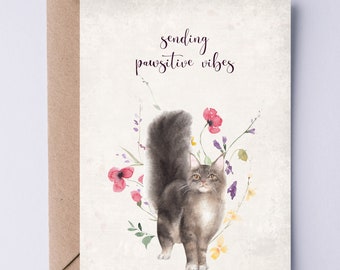 Könnte beinhalten: Eine Aquarell-Illustration einer grauen Katze mit einem buschigen Schwanz, die in einem Blumenfeld steht. Der Text "sending pawsitive vibes" steht über der Katze.