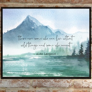Könnte beinhalten: Ein Aquarellbild einer Bergkette mit einem See im Vordergrund. Das Zitat "Es gibt Menschen, die ohne Wildnis leben können, und andere, die es nicht können - Aldo Leopold" ist auf dem Bild geschrieben.
