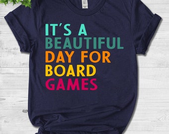 May include: A navy blue t-shirt with the text "It's a beautiful day for board games" in rainbow colours.